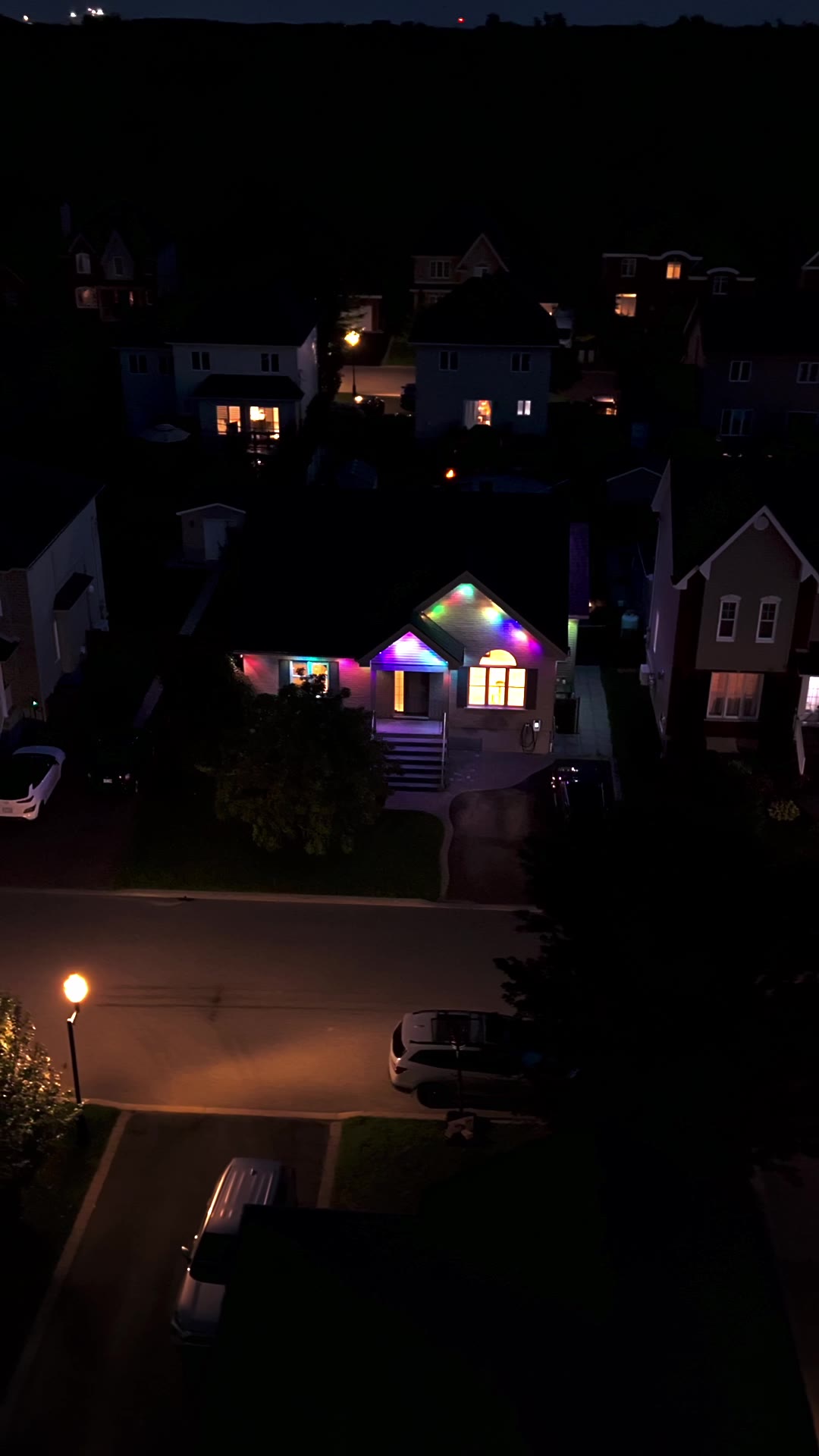 Vue aérienne de nuit : une maison illuminée se démarque dans son quartier