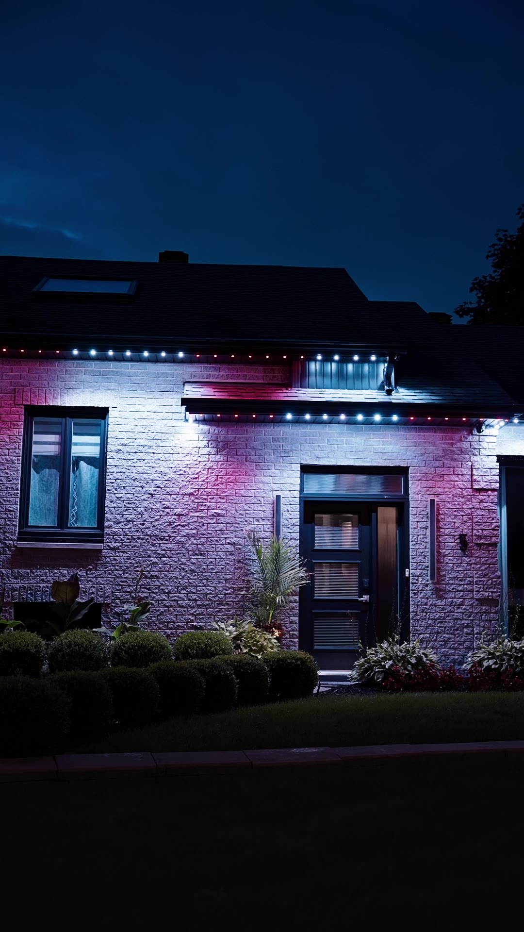 Maison moderne éclairée en bleu, blanc et rouge au crépuscule